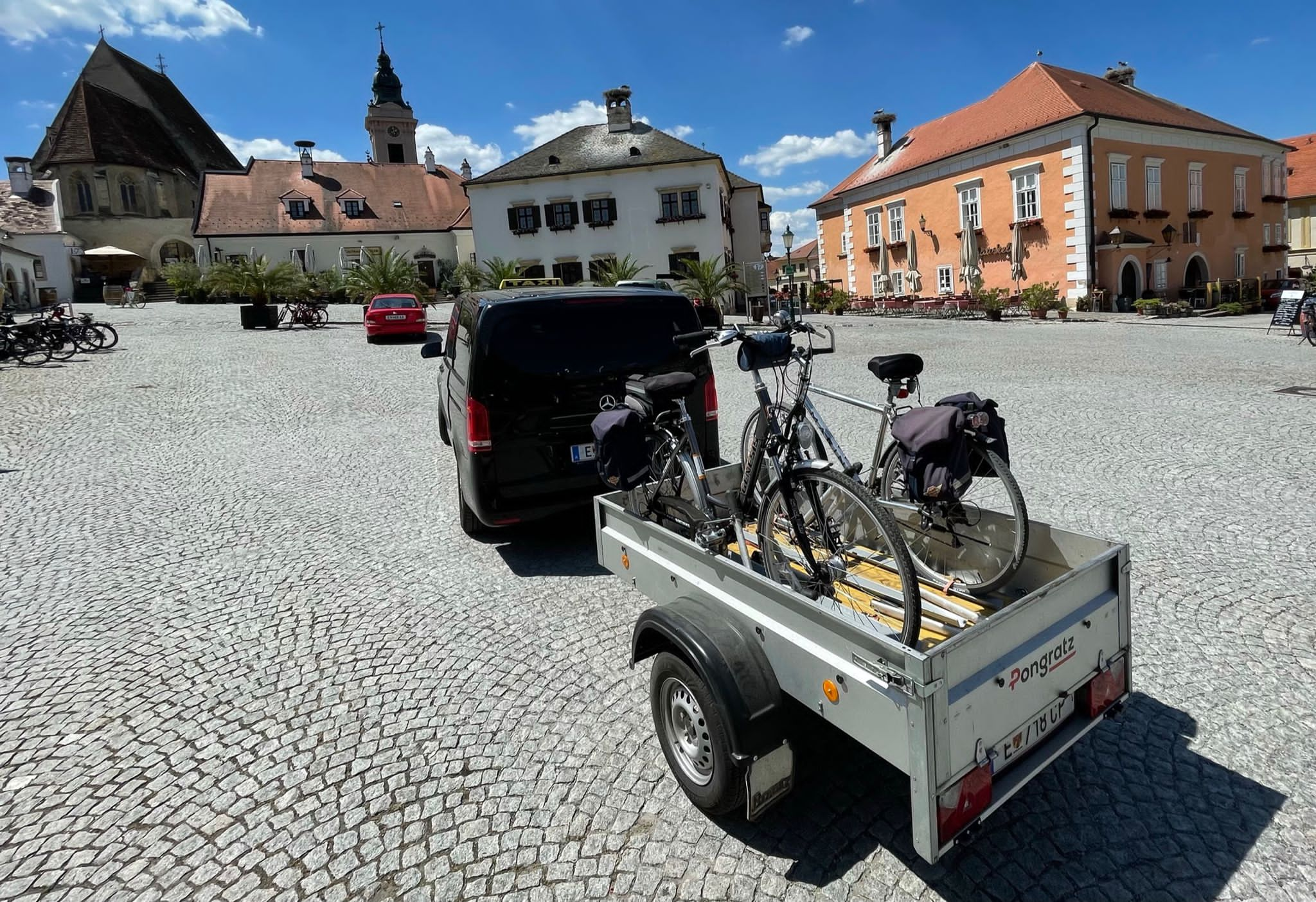 Schwarzes Taxi mit fahrradbeladenem Anhänger